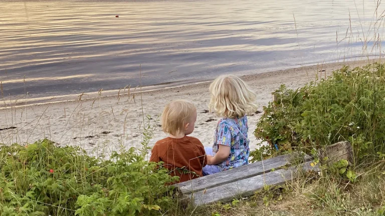 to børn sidder på en trappe og kigger ud over vandet